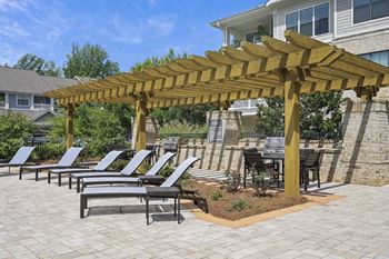 a patio with lounge chairs under a wooden pergola